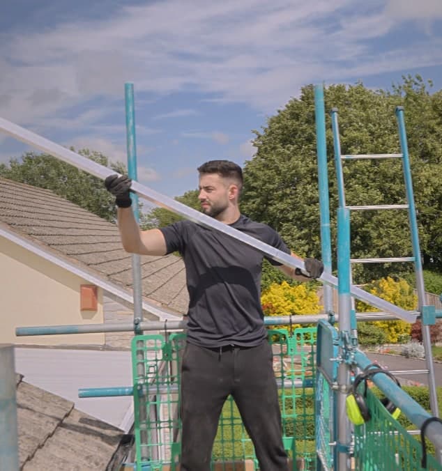 A Geko engineer carrying a panel up the scaffolding rail